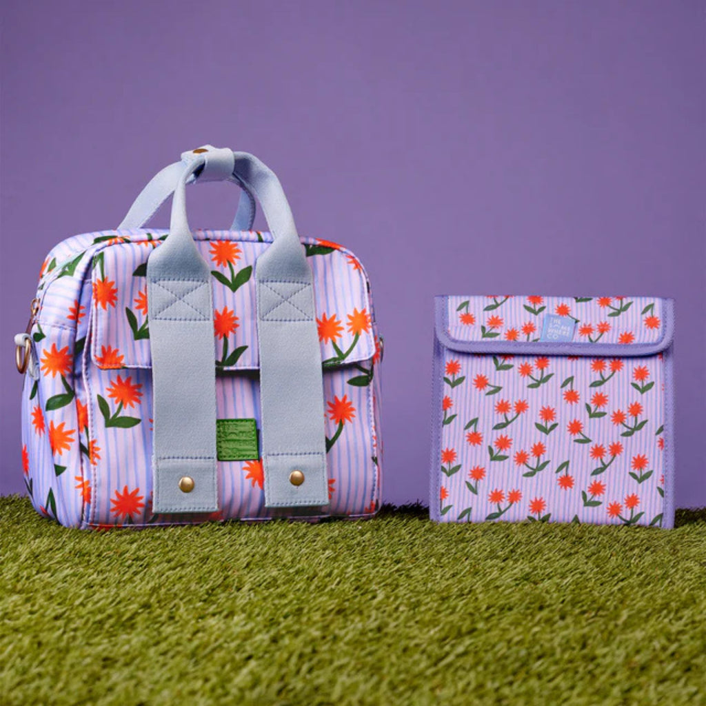 Floral-patterned backpack and pouch on a grassy surface with a purple background
