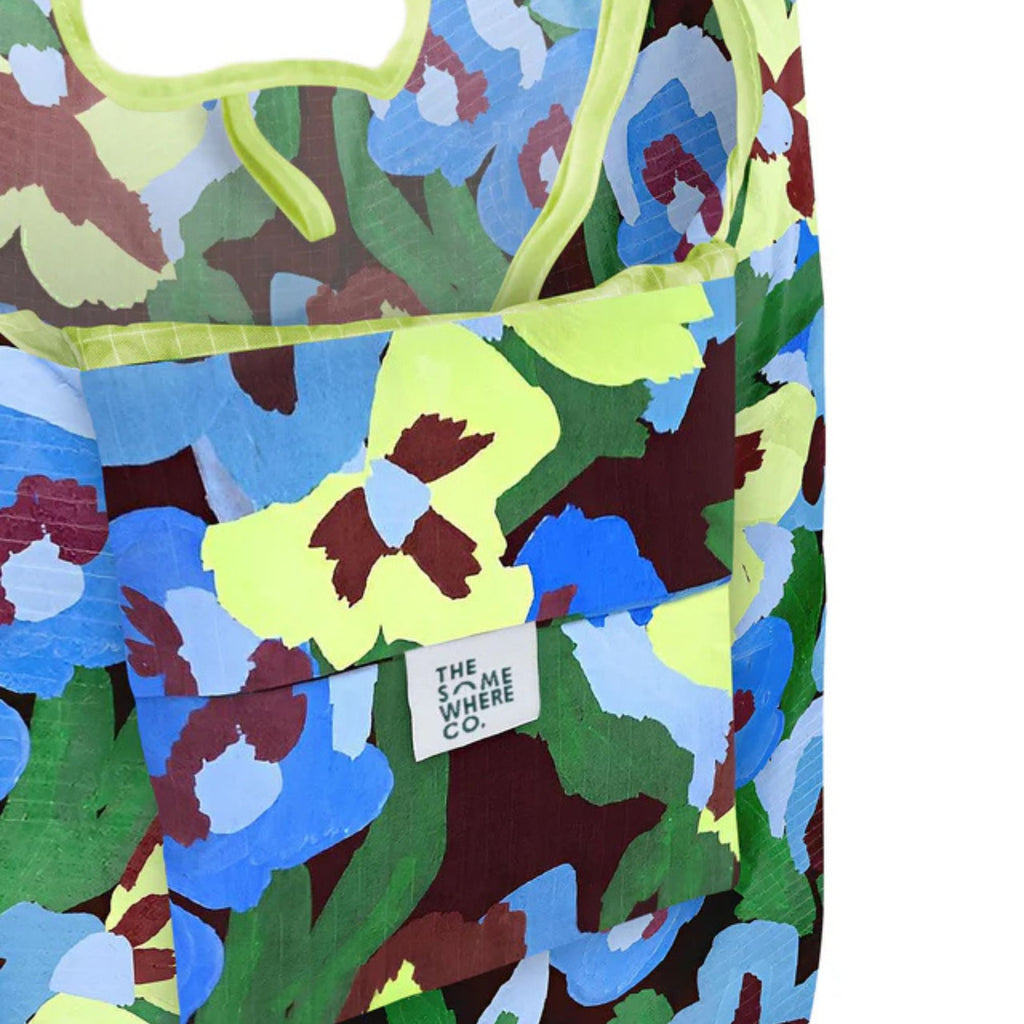 Colorful floral-patterned apron with a brand tag on a white background