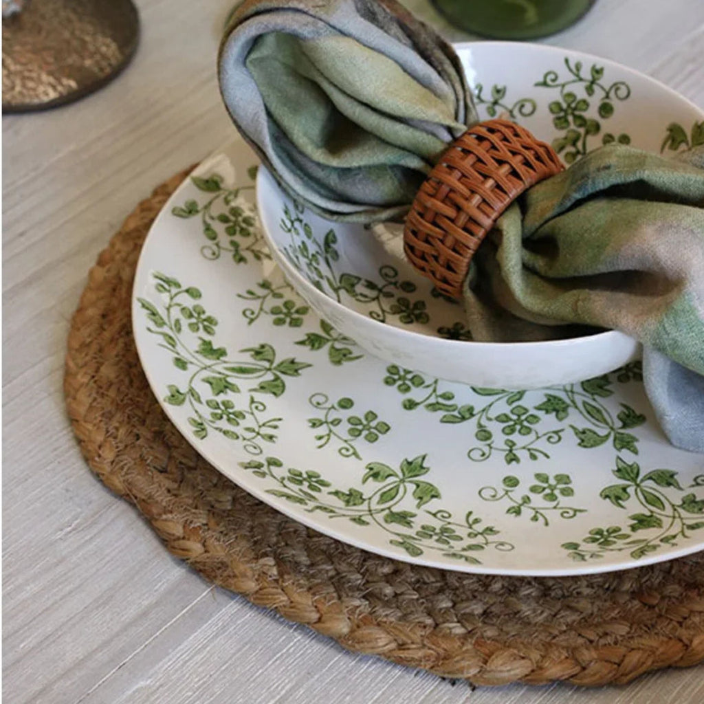 table setting with white plates with green pattern on a round jute placemat