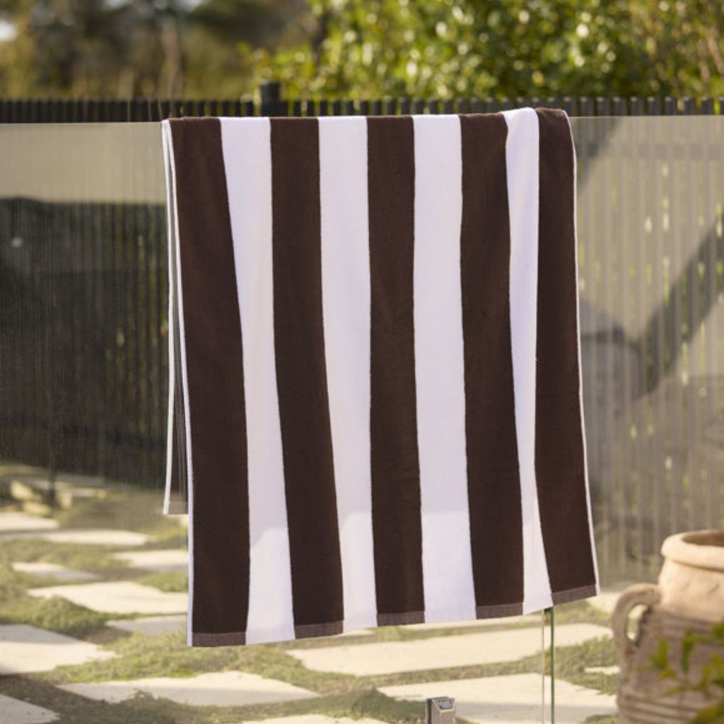 Striped brown and white towel hanging on a fence outdoors