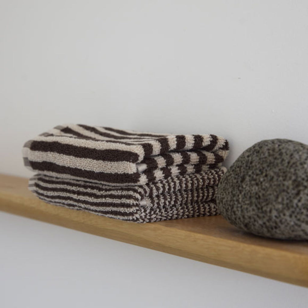 Folded striped socks on a wooden shelf with a white background