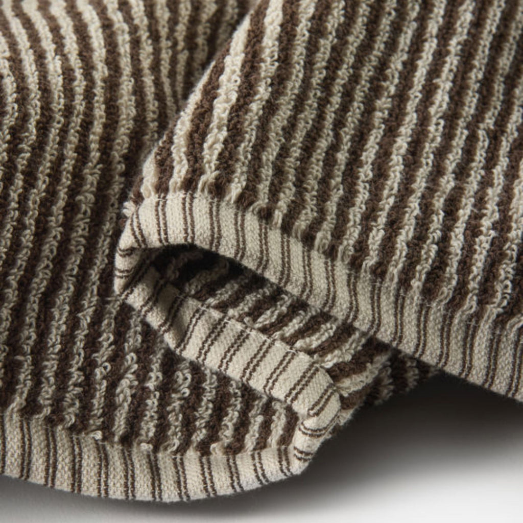 Close-up of brown and beige striped fabric with a textured pattern.