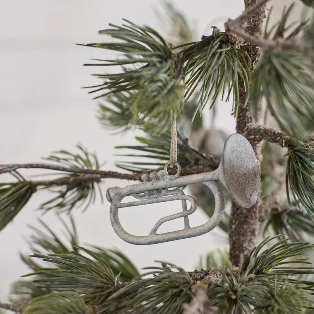 Decorative silver trumpet ornament on a Christmas tree branch