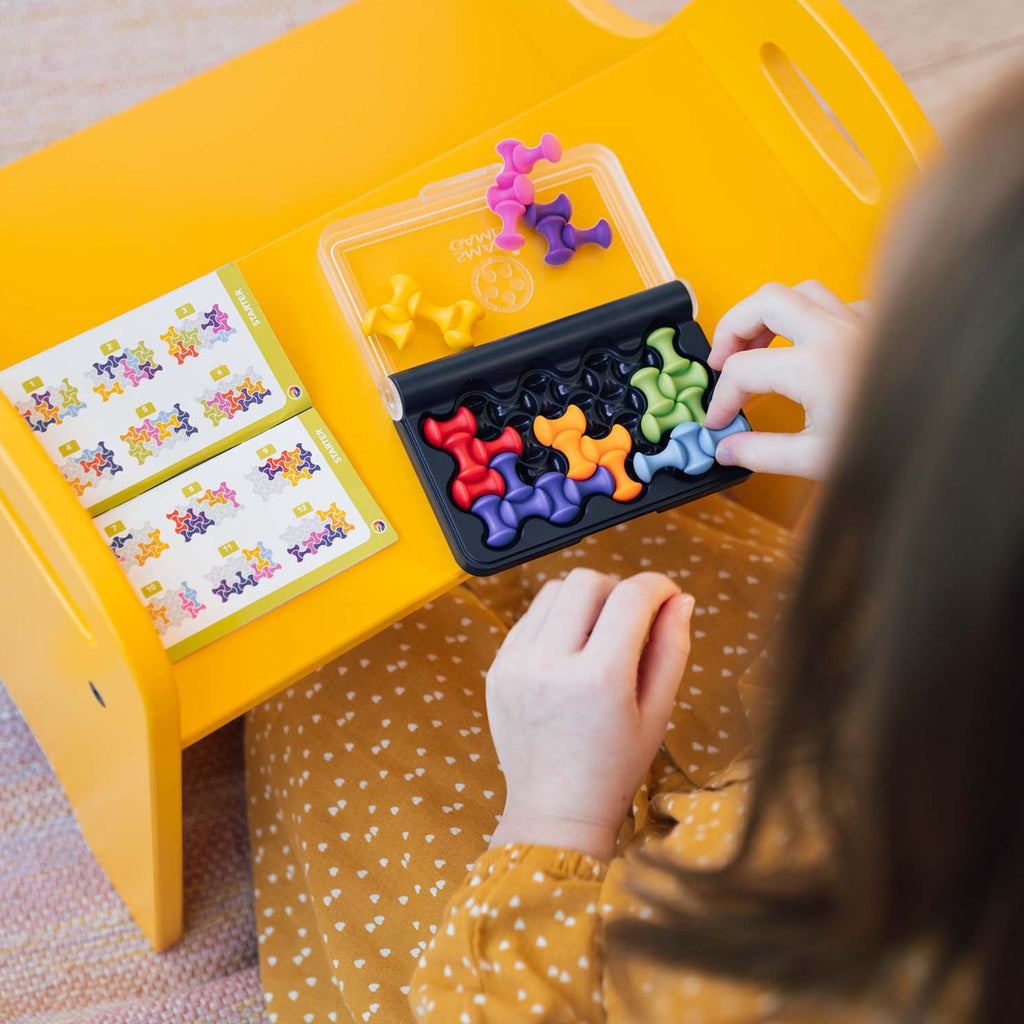 Child playing with a colorful puzzle on a yellow table