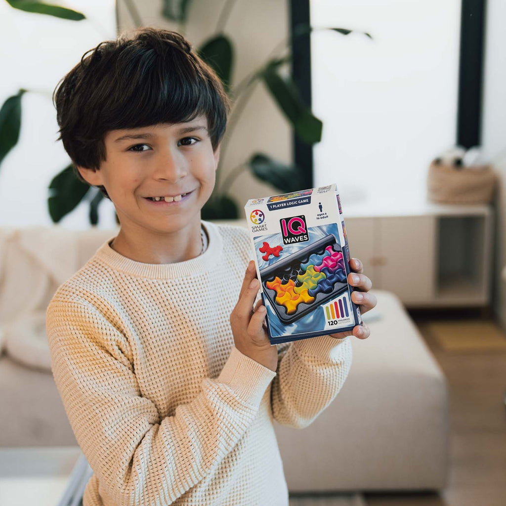 Child holding a colorful IQ toy packaging in a living room setting