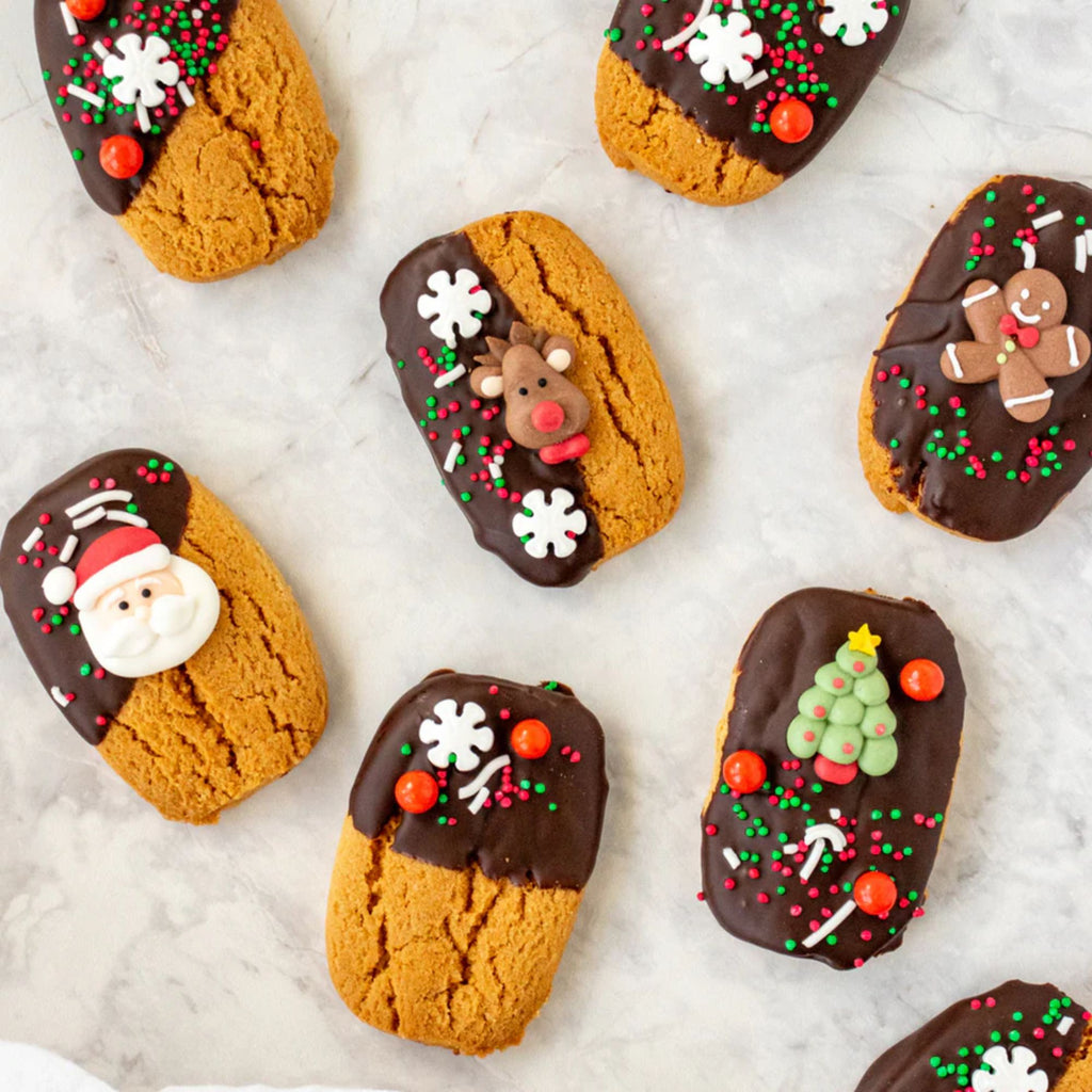 A variety of 8 cookies decorated in chocolate and Christmas sprinkles on a marble bench-top