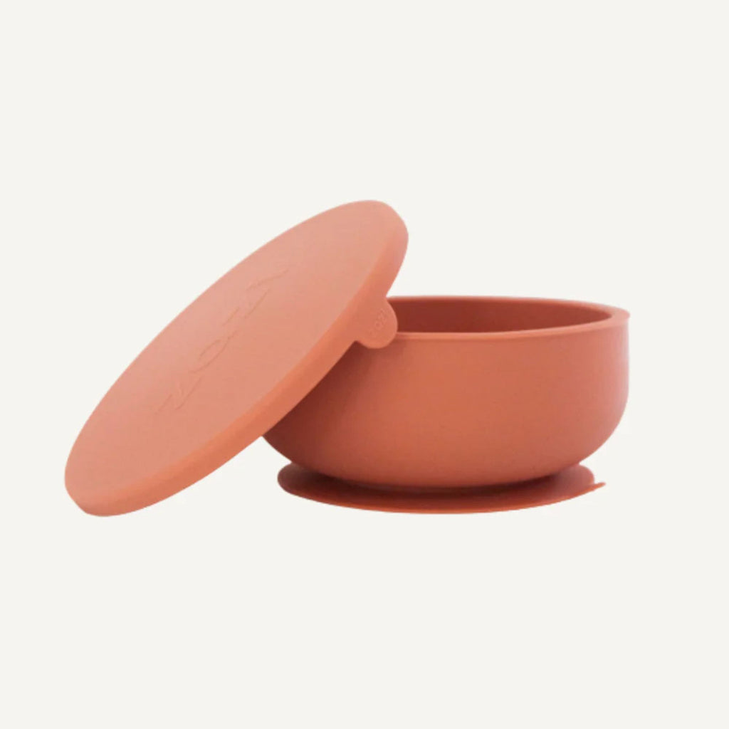 Terracotta-colored bowl with lid on a white background