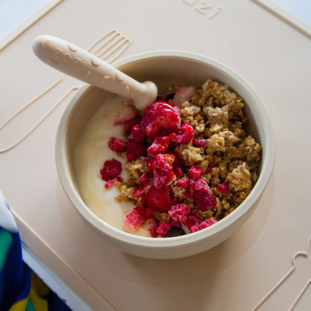 Bowl of yogurt with granola and berries on a child's plate