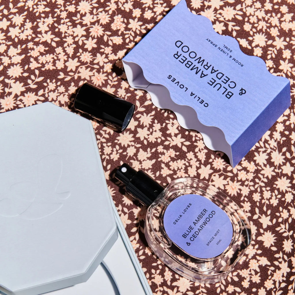 Perfume bottle and packaging with 'Blue Amber & Cedarwood' on a floral patterned surface