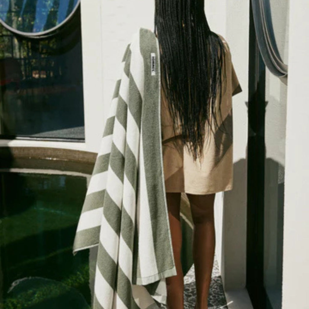 Person holding a striped towel by a poolside