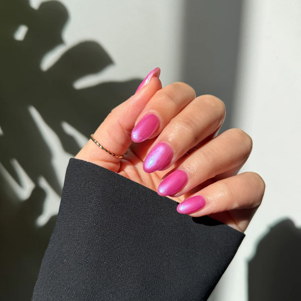 Hand with pink nails holding a black sleeve against a light background