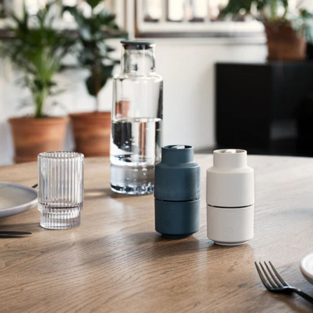 Three cylindrical containers on a wooden table with a blurred indoor background