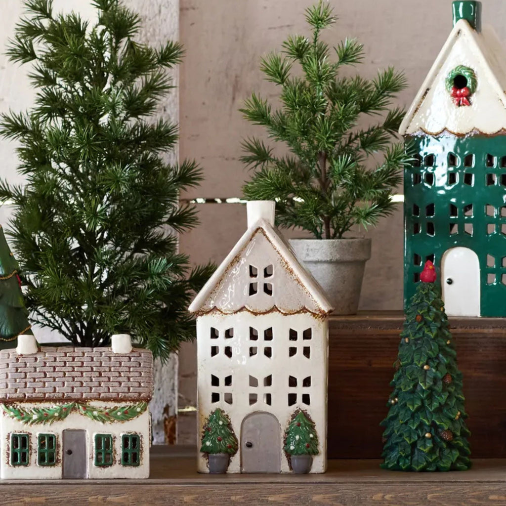 Decorative ceramic houses with Christmas trees on a wooden surface.