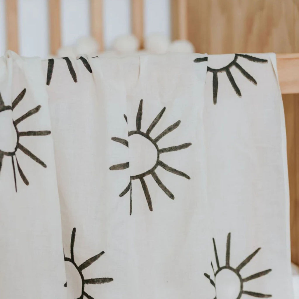 White towel with black sun patterns draped over a wooden surface