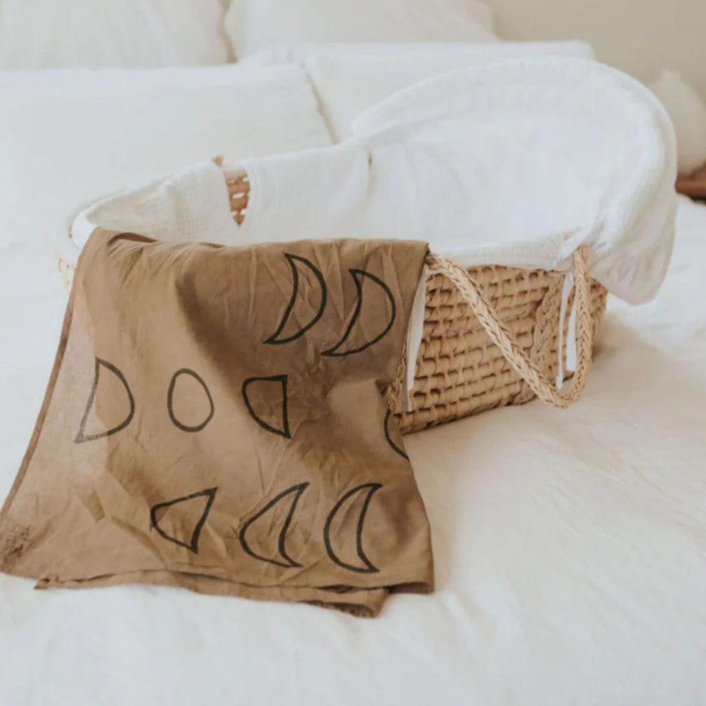 Brown fabric with black symbols draped over a wicker basket on a white surface