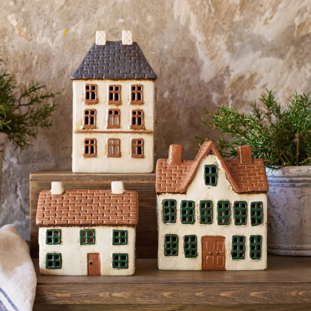Set of ceramic house-shaped decorative items on a wooden surface with a neutral background.