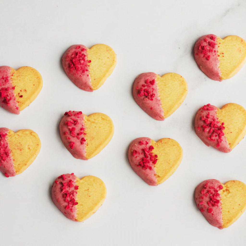 Heart-shaped cookies with pink and yellow halves on a white background