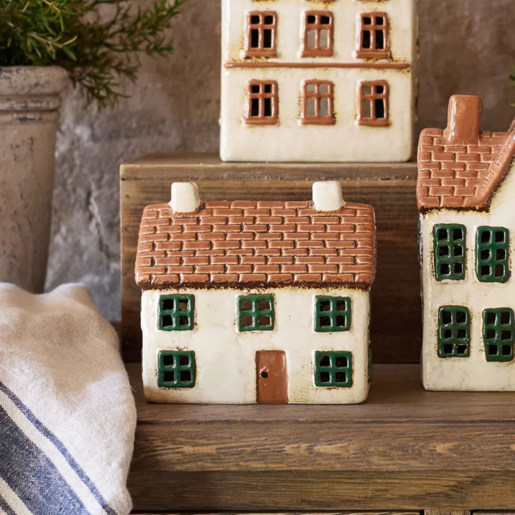Set of ceramic houses on a wooden surface with a neutral background