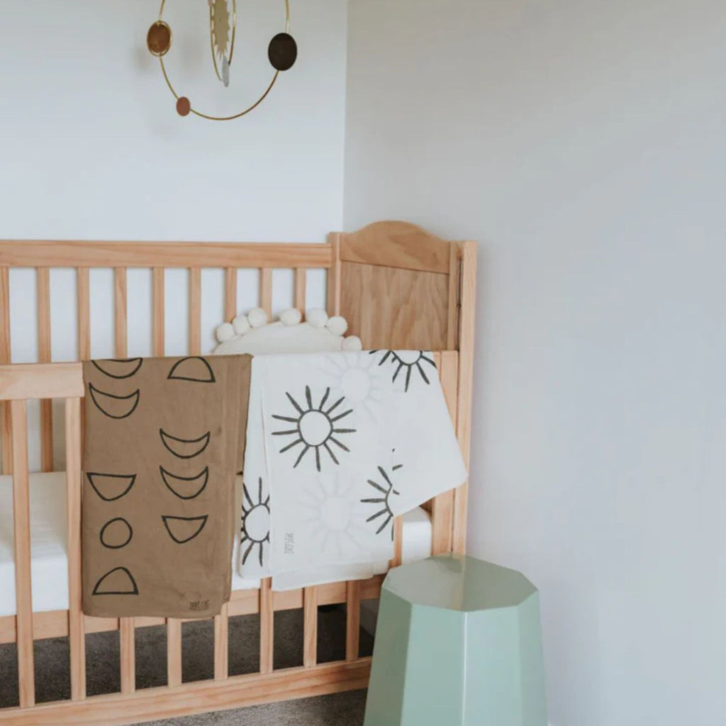 Wooden crib with patterned blankets in a minimalistic room