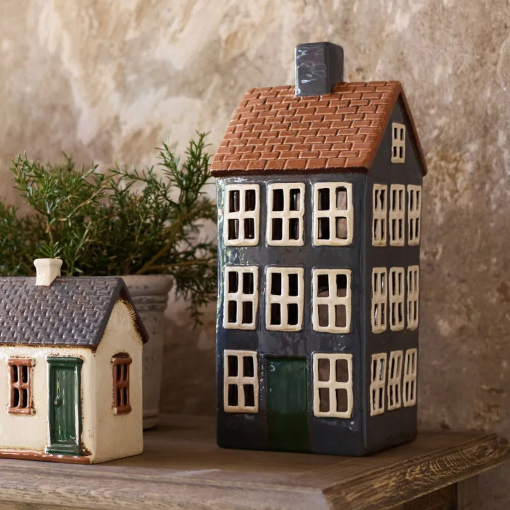 Two ceramic house models on a wooden surface with a textured wall background.