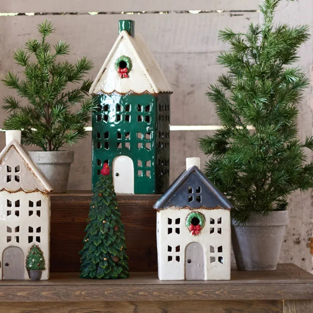 Decorative ceramic houses with Christmas trees on a wooden surface