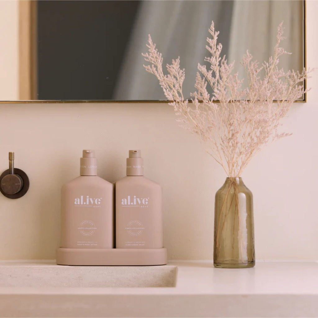 Two bottles labeled 'alive' on a shelf with a vase of dried flowers.