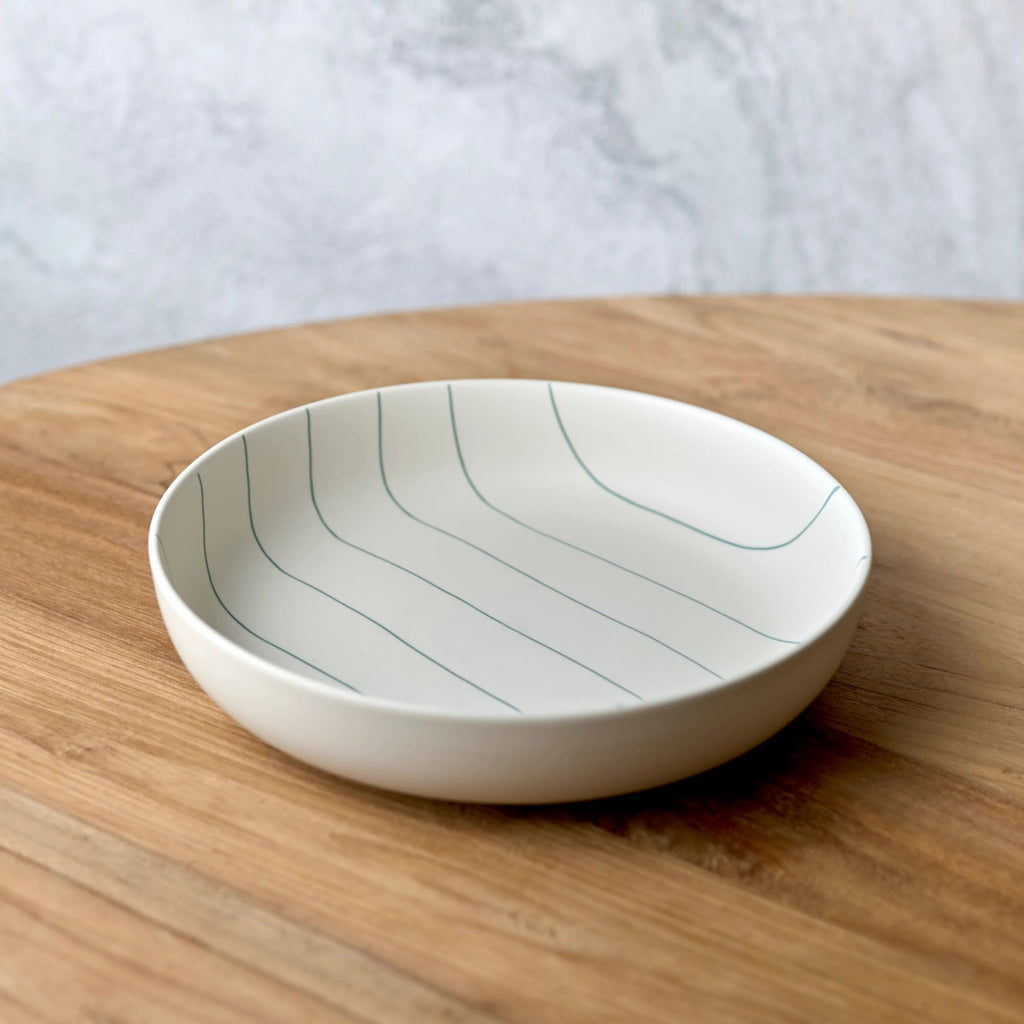 White ceramic bowl with wavy lines on a wooden surface