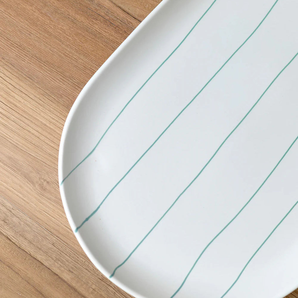 White ceramic tray with blue lines on a wooden surface
