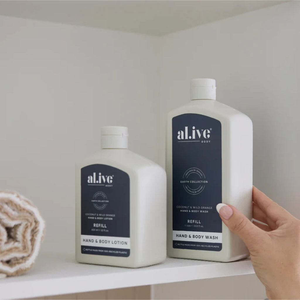 Two bottles of 'al.ive' hand and body products on a shelf with a hand reaching for one.