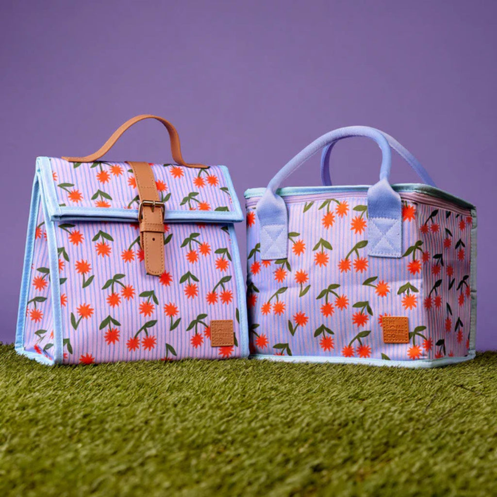 Two floral-patterned bags on a grassy surface with a purple background