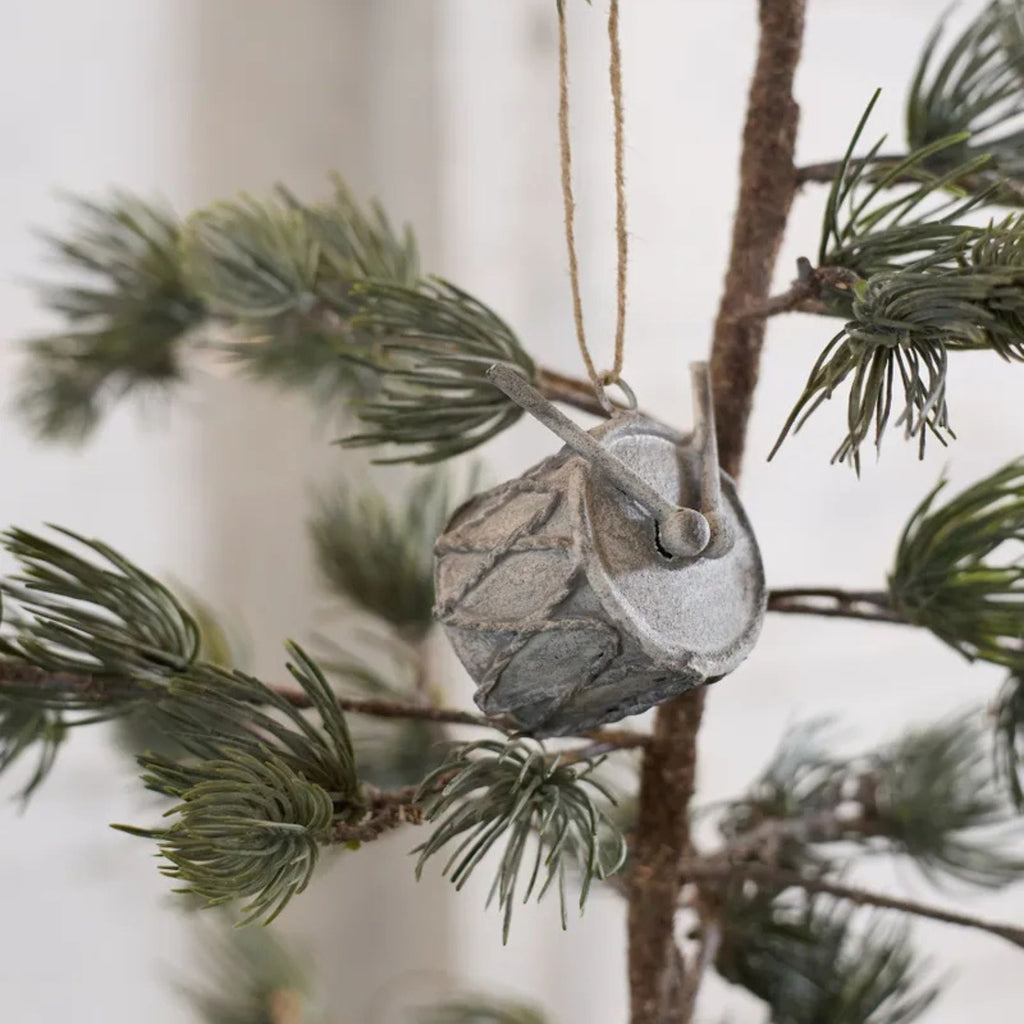 Decorative =ornament shaped like a drum  hanging on a tree branch.