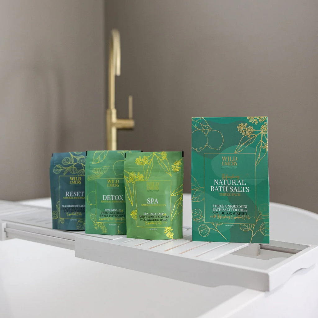 Green packages of bath salts on a white surface with a neutral background