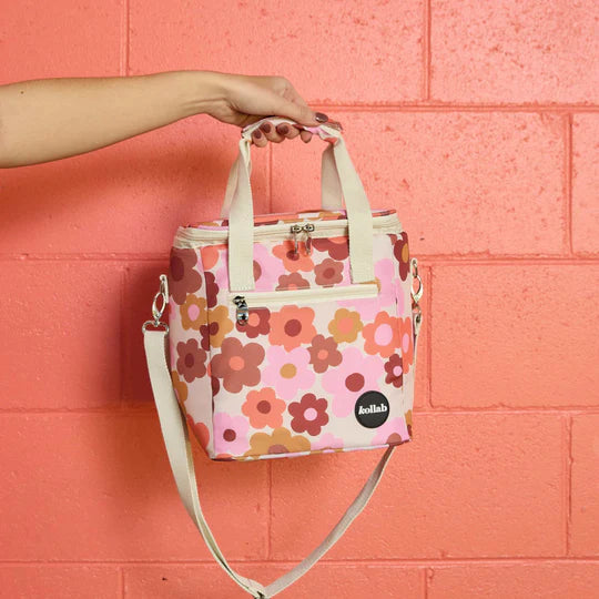 Floral-patterned bag held against a pink brick wall