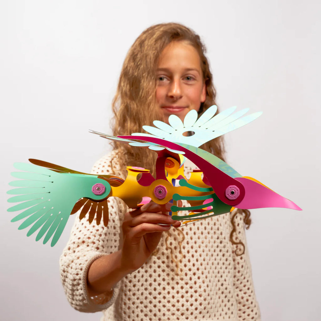 Person holding a colorful paper bird sculpture against a plain background