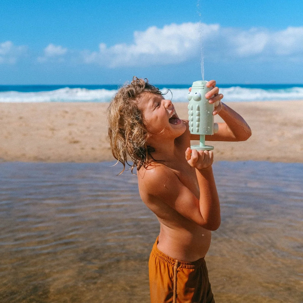 Child playing with a toy water gun on a beach
