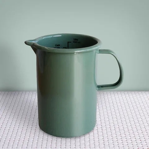 Green pitcher on a textured surface with a light green background