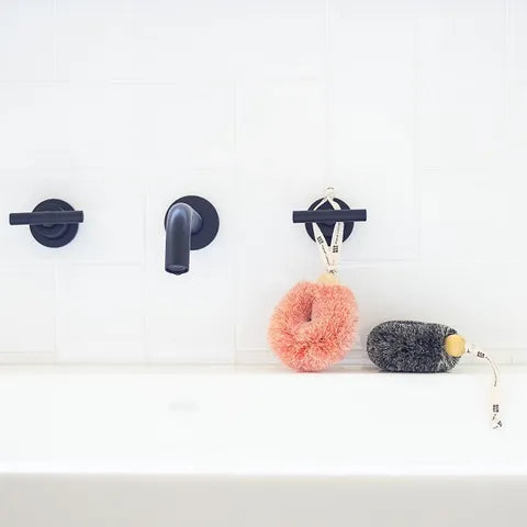 Two wall hooks with a pink fuzzy ball and a gray mouse-shaped object on a white background.