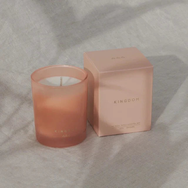 Pink candle and box with 'Kingdom' branding on a textured surface