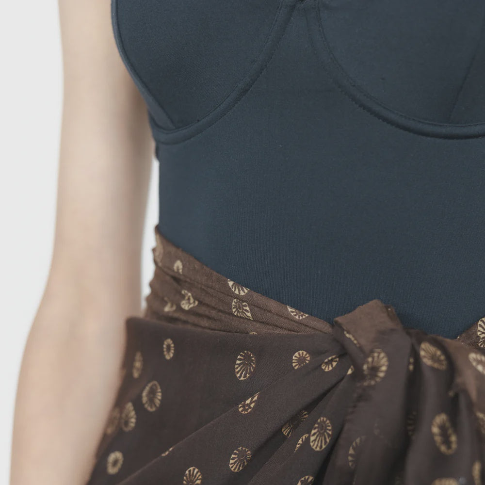 Woman's midriff wearing black togs and a scarf tried around waste 