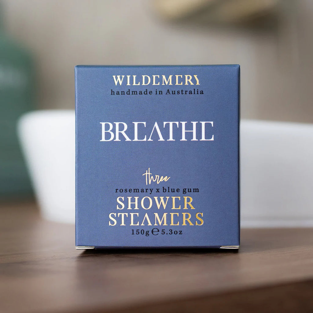 Box of Wildemery Breathe shower steamers on a wooden surface with a blurred background