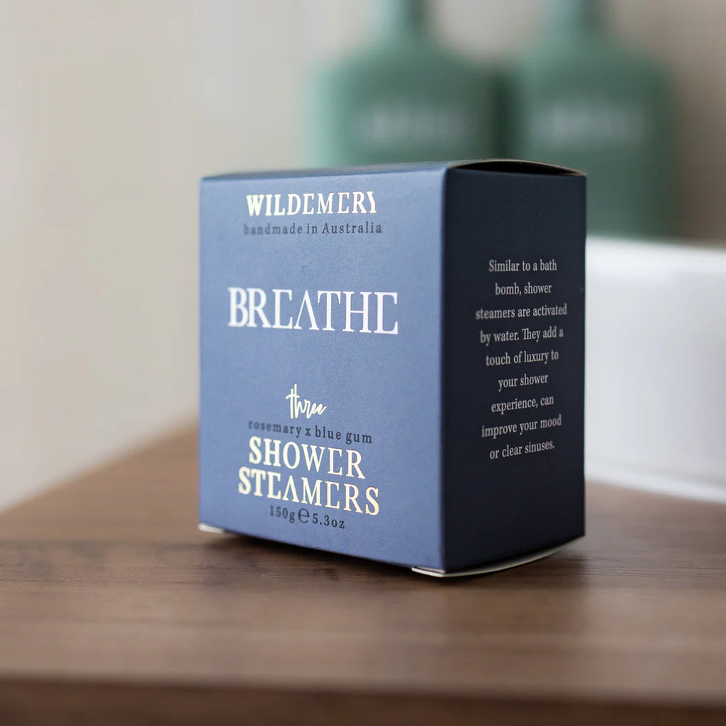 Box of Wildemere Breathe shower steamers on a wooden surface with a blurred background.