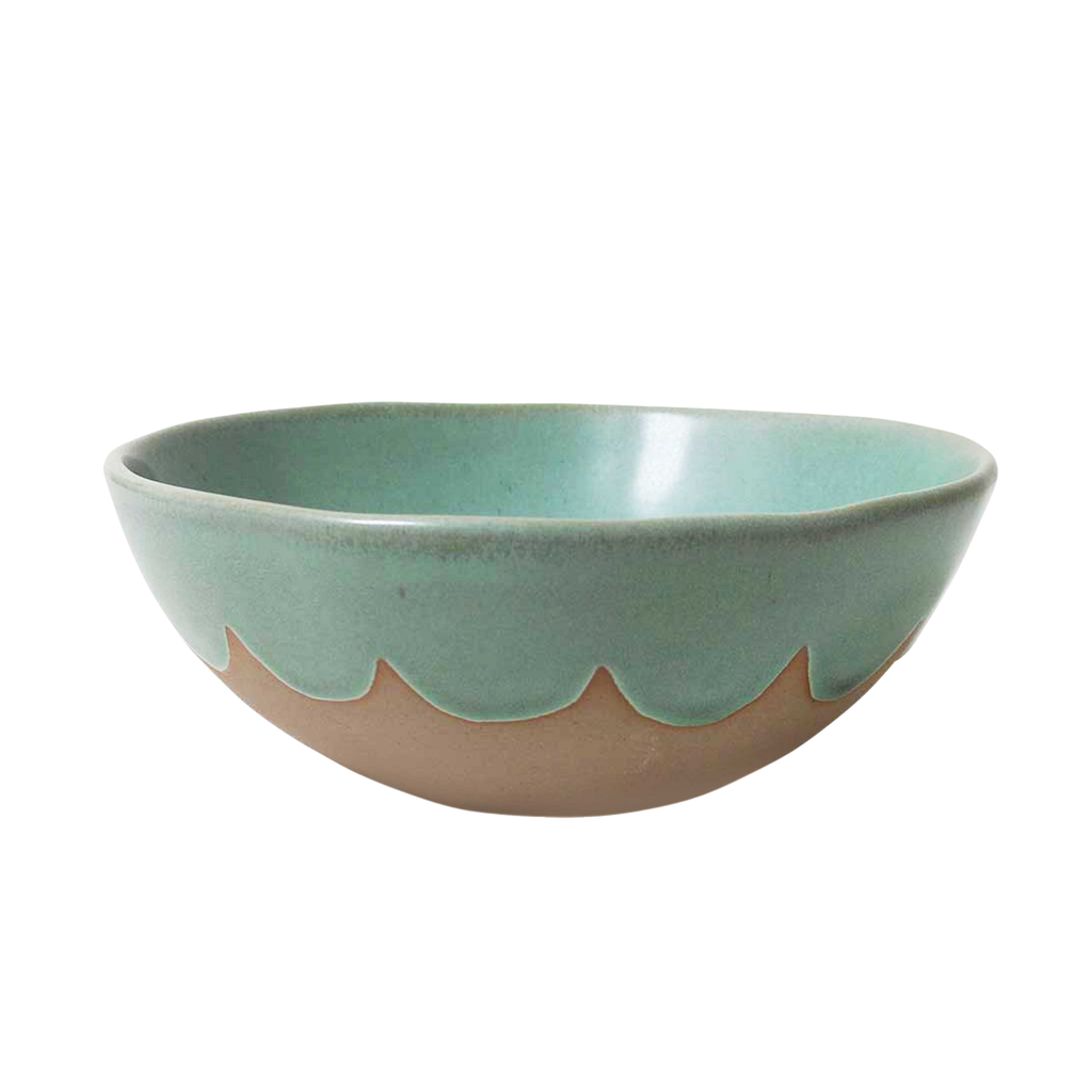 A ceramic mixing bowl with a green scalloped inner and edge glaze and a beige bisque bottom, placed on a flat surface against a white background.
