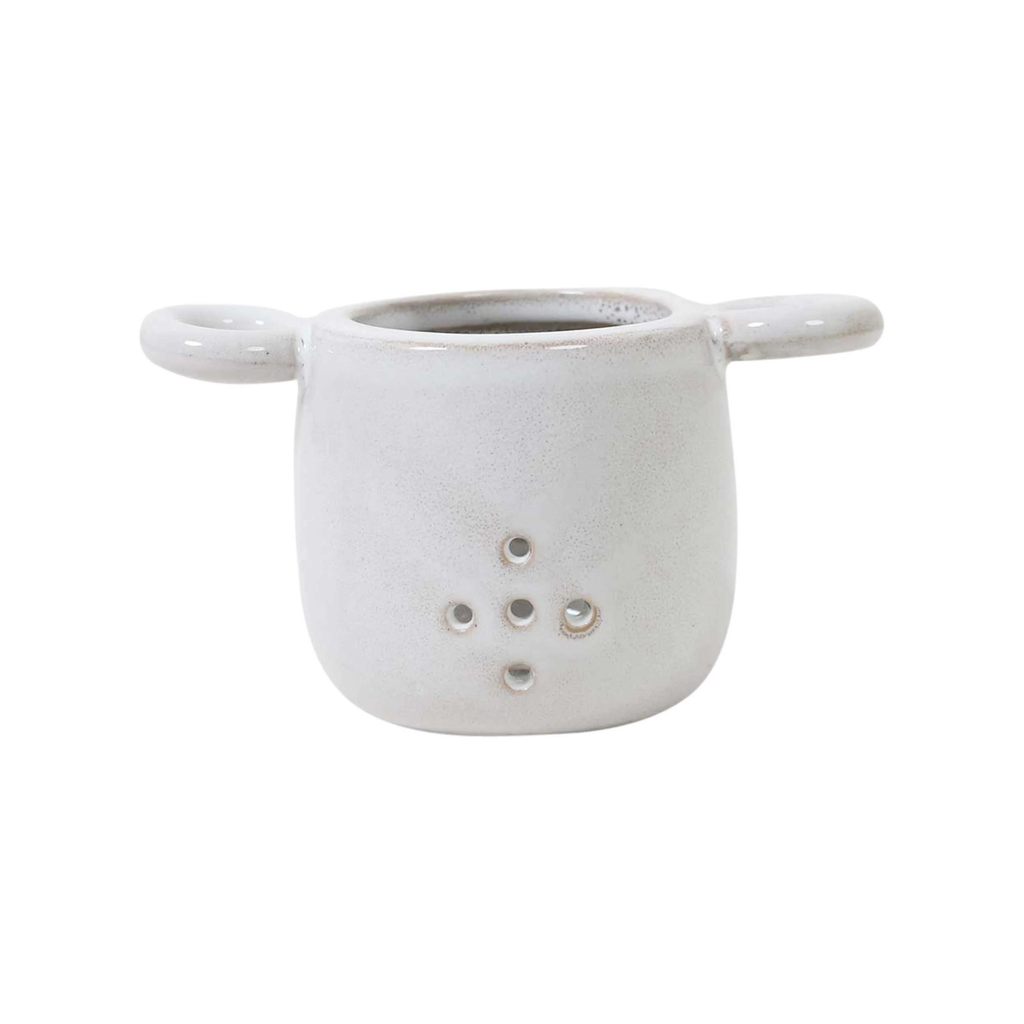 A white ceramic tea strainer against a white background 