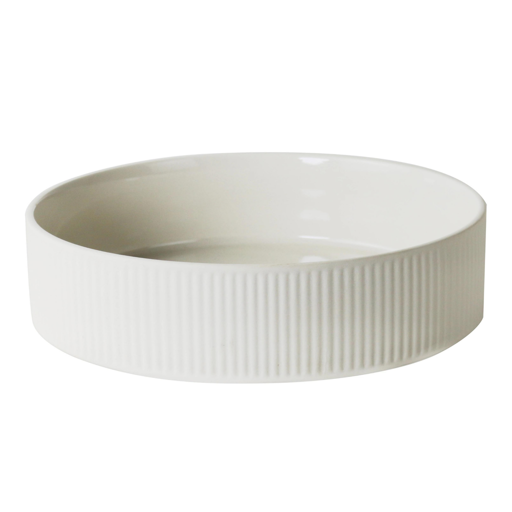 A white ribbed flat sitting salad bowl against a white background 